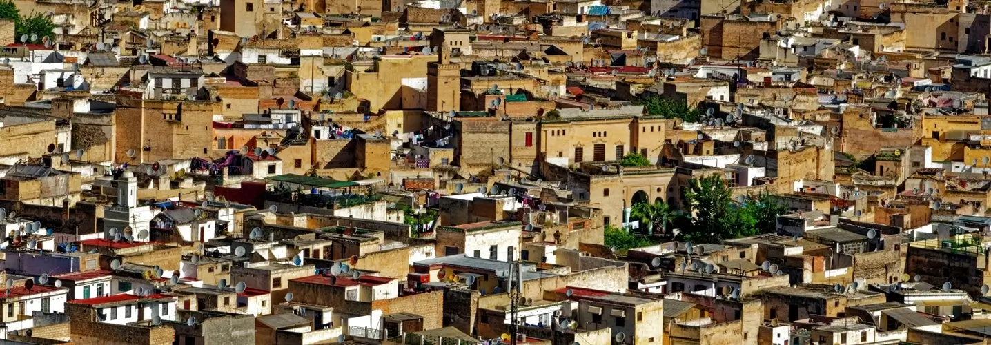 Dense aerial view of the historic Medina of Fes, showcasing a sea of traditional buildings with satellite dishes, marking the start of a 3 days journey from Fes to the desert